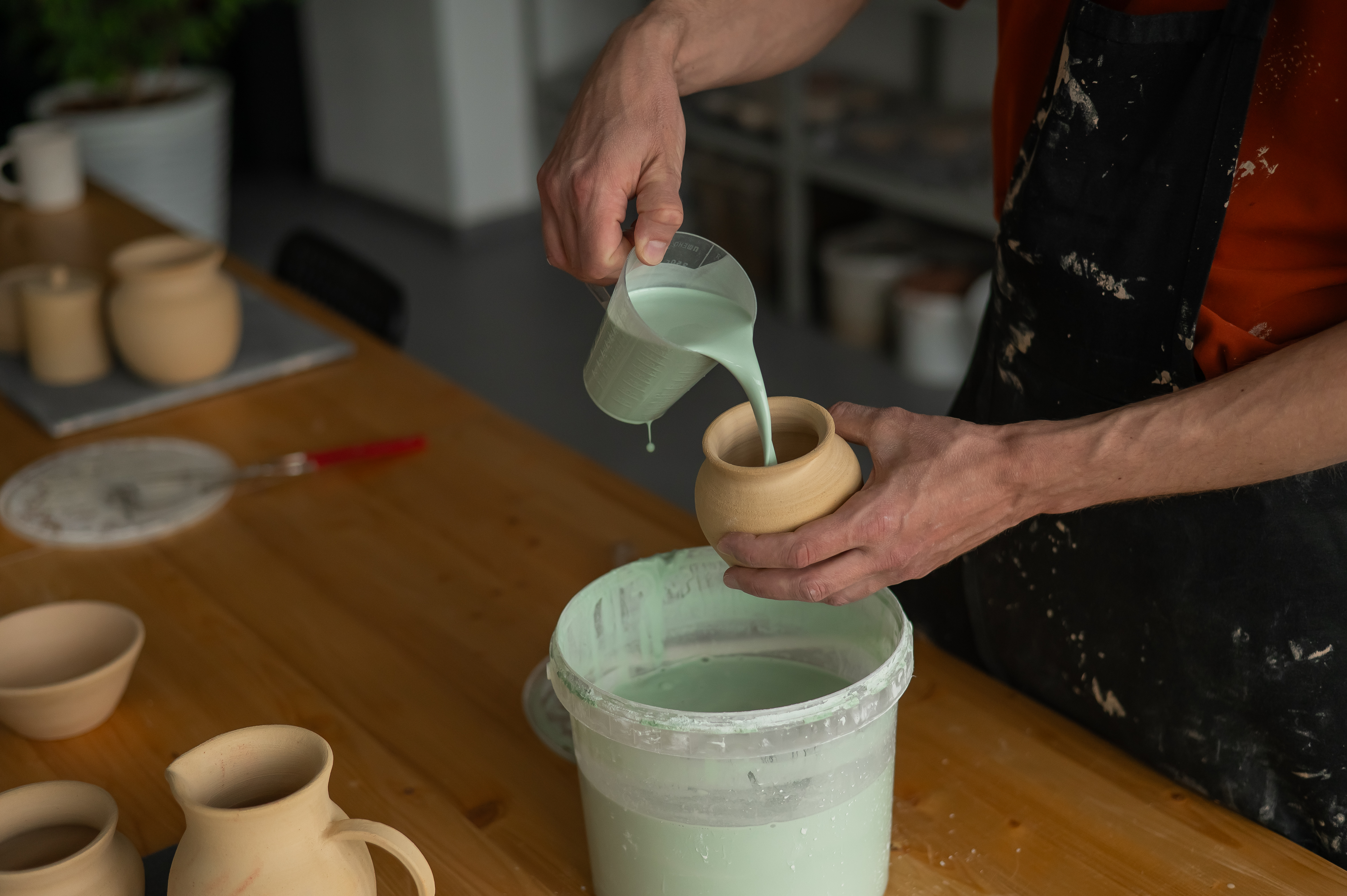 man pouring glaze onto project