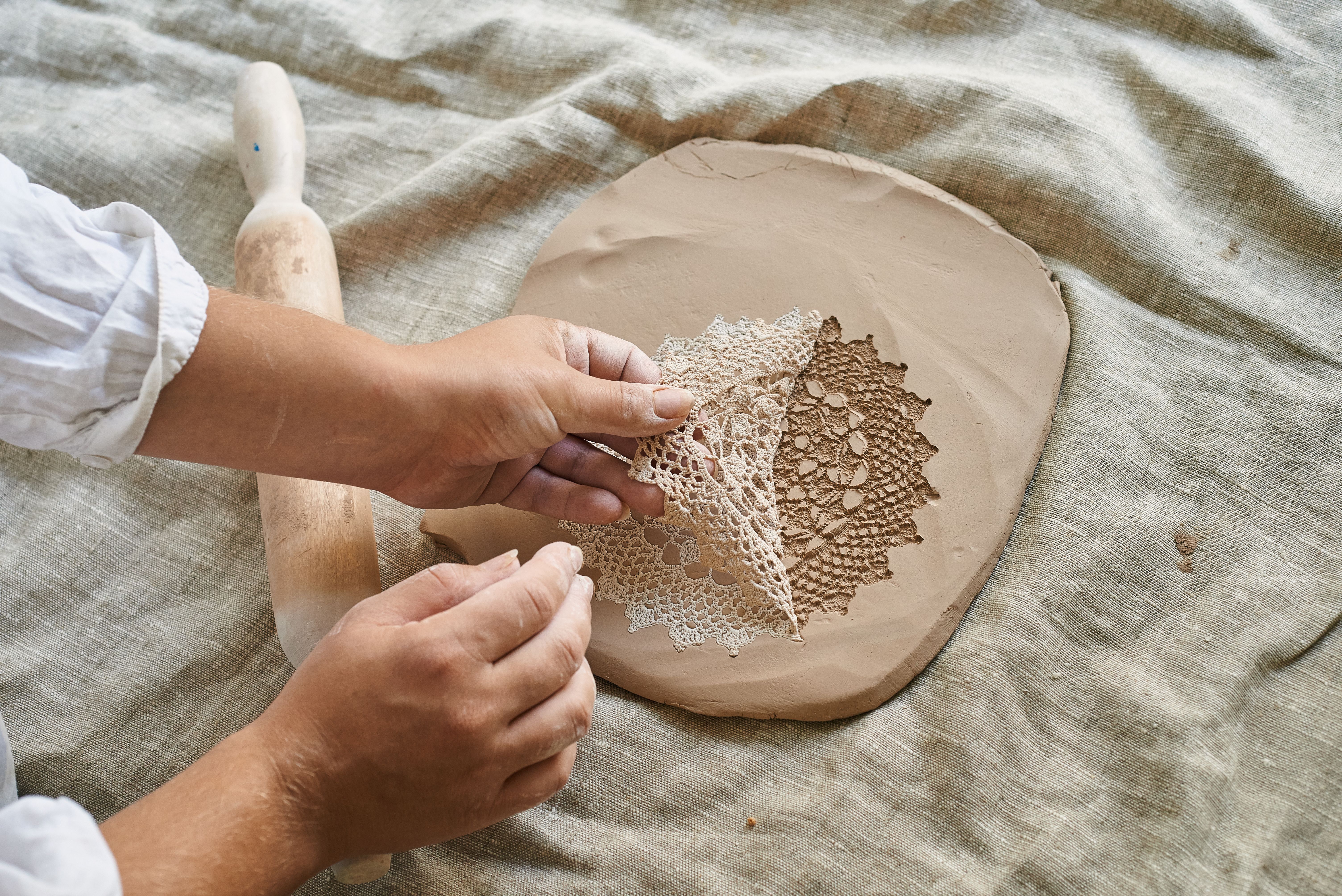 woman adding texture to clay with lace